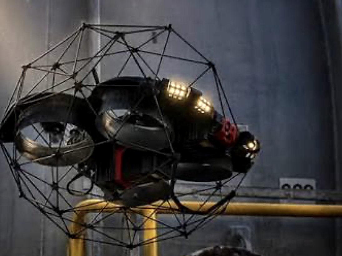 Inspectiedrone in beschermkooi met verlichting bij een tank